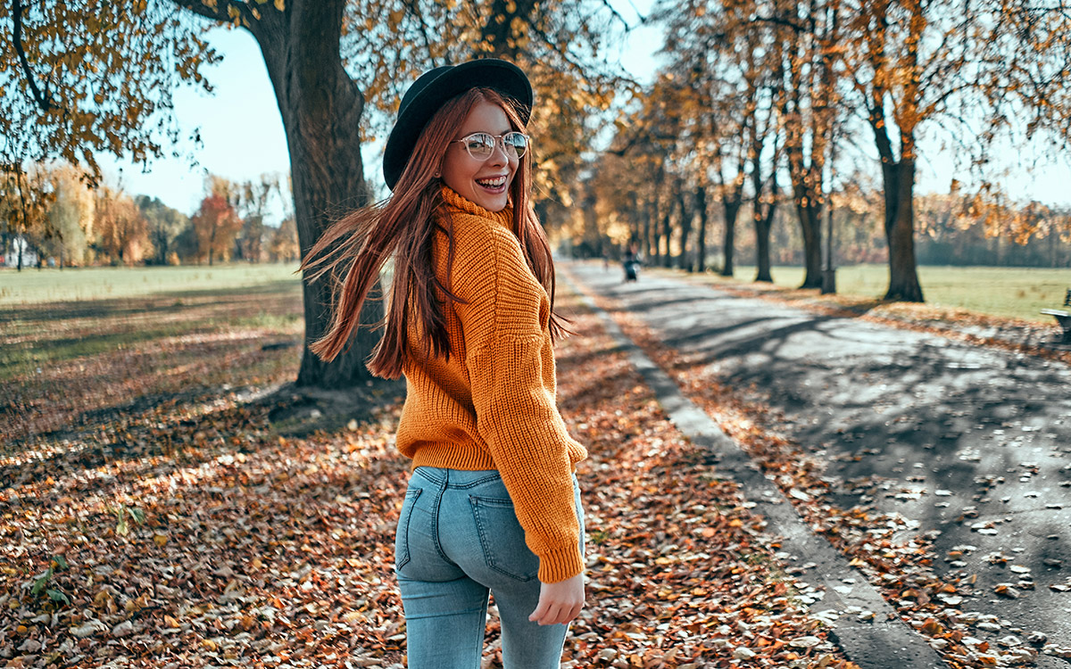 Young teenage redhead girl walking down a street in autumn.