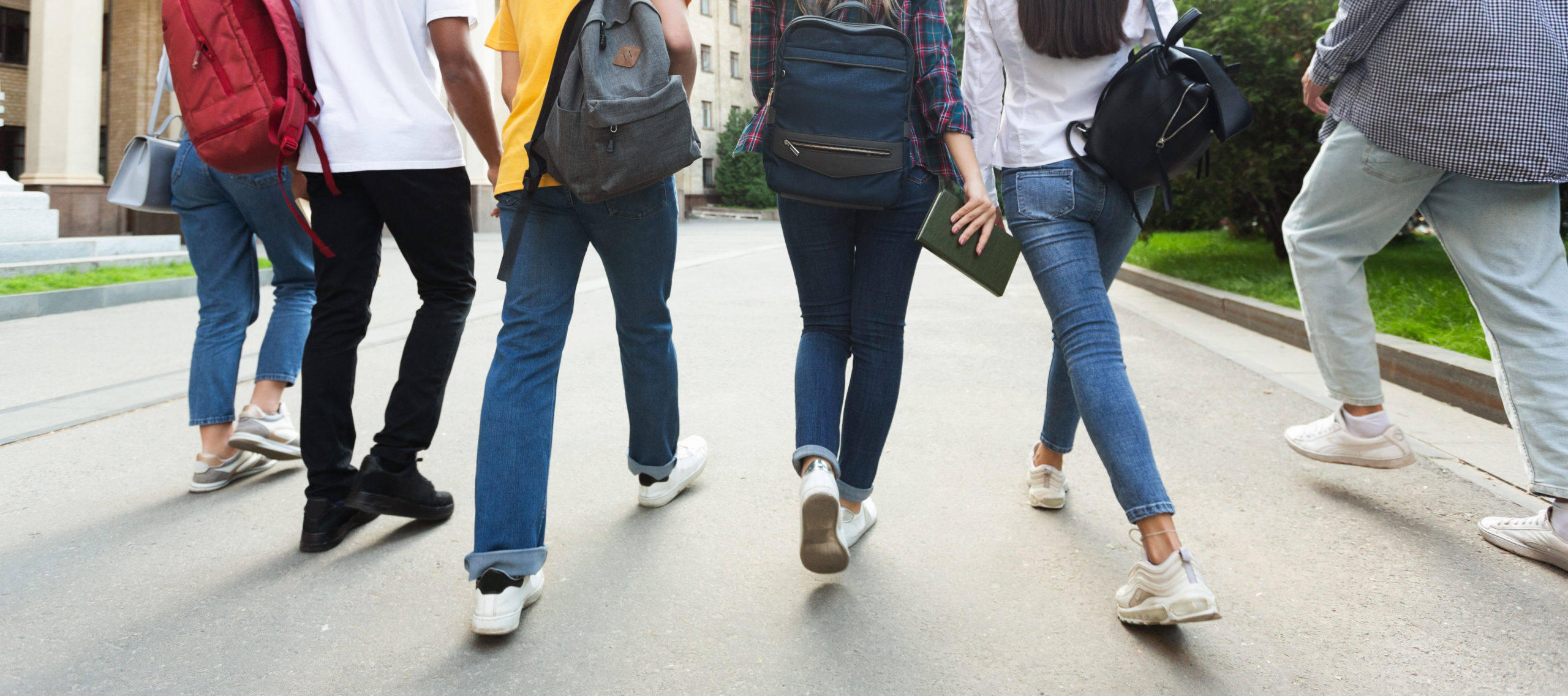Teens going back to school, walking together on campus.