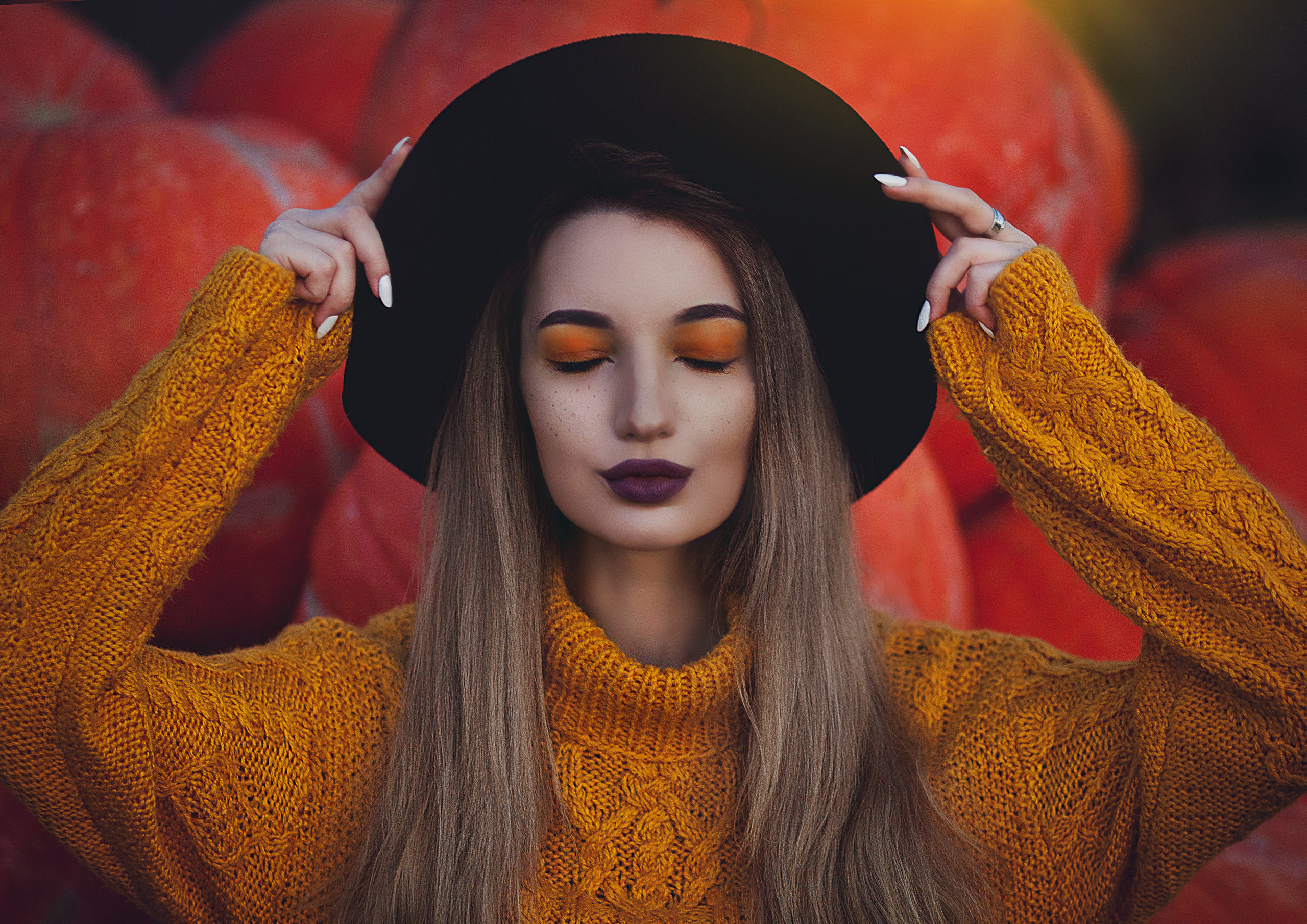 Teen girl getting made up for Halloween, with pumpkins in the background.