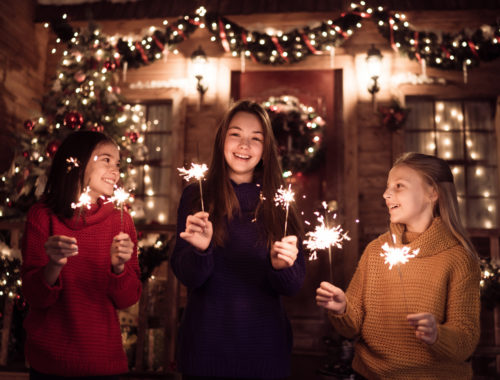 Three young girls celebrating New Year’s Eve together with sparklers.